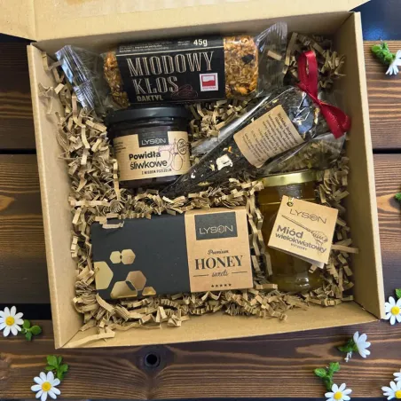 Wnętrze brązowego pudełka z miodami i produktami Lyson oraz herbatką Eterno ułożonymi na wypełniaczu