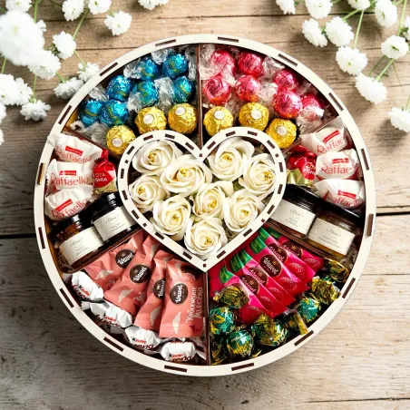 Wnętrze ślubnego pudełka z białymi różami, sercem i słodką kompozycją