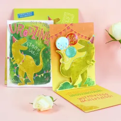 Karnet pop-up z dinozaurem, zieloną kopertą i urodzinowymi życzeniami.
