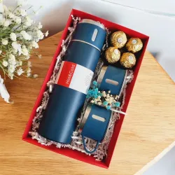 Otwarte czerwone pudełko z kubkiem termicznym i słodkościami ułożonymi obok siebie