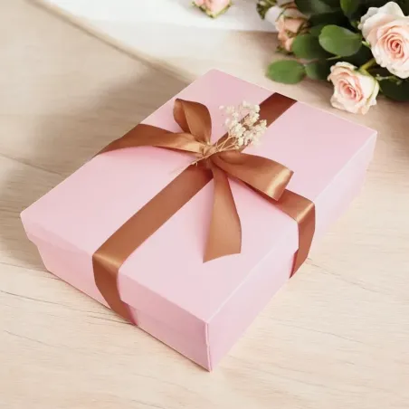 Zamknięte pastelowe różowe pudełko przewiązane złotą wstążką