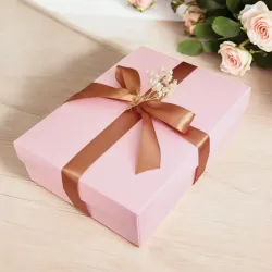 Zamknięte różowe pudełko przewiązane złotą wstążką