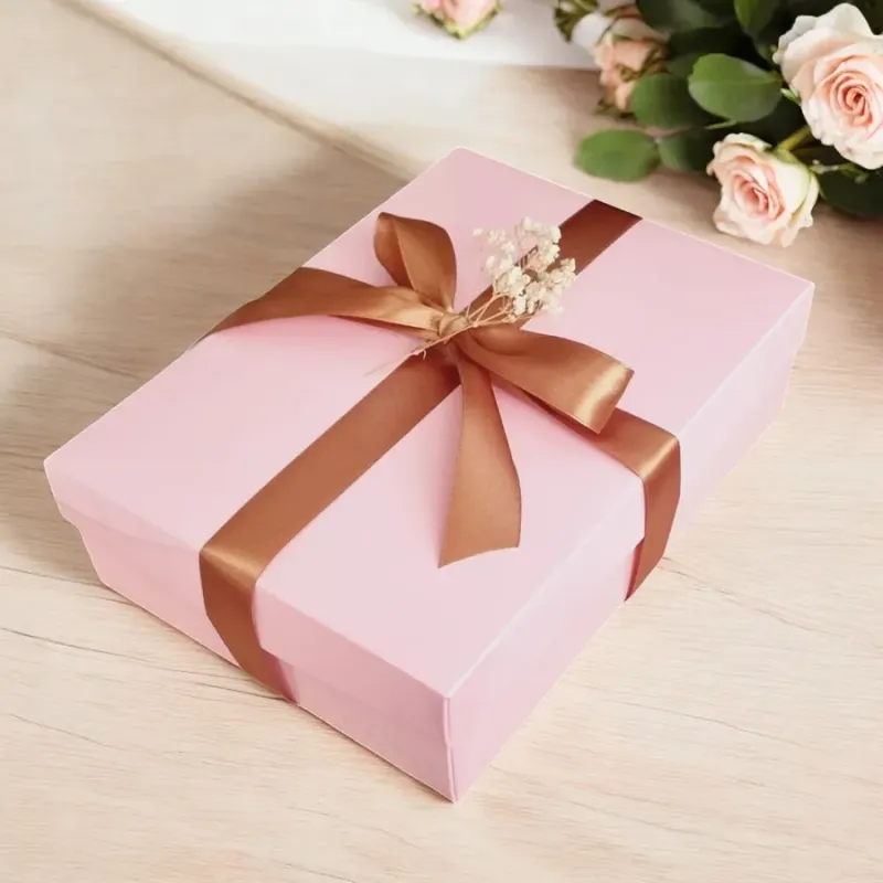 Zamknięte różowe pudełko przewiązane złotą wstążką