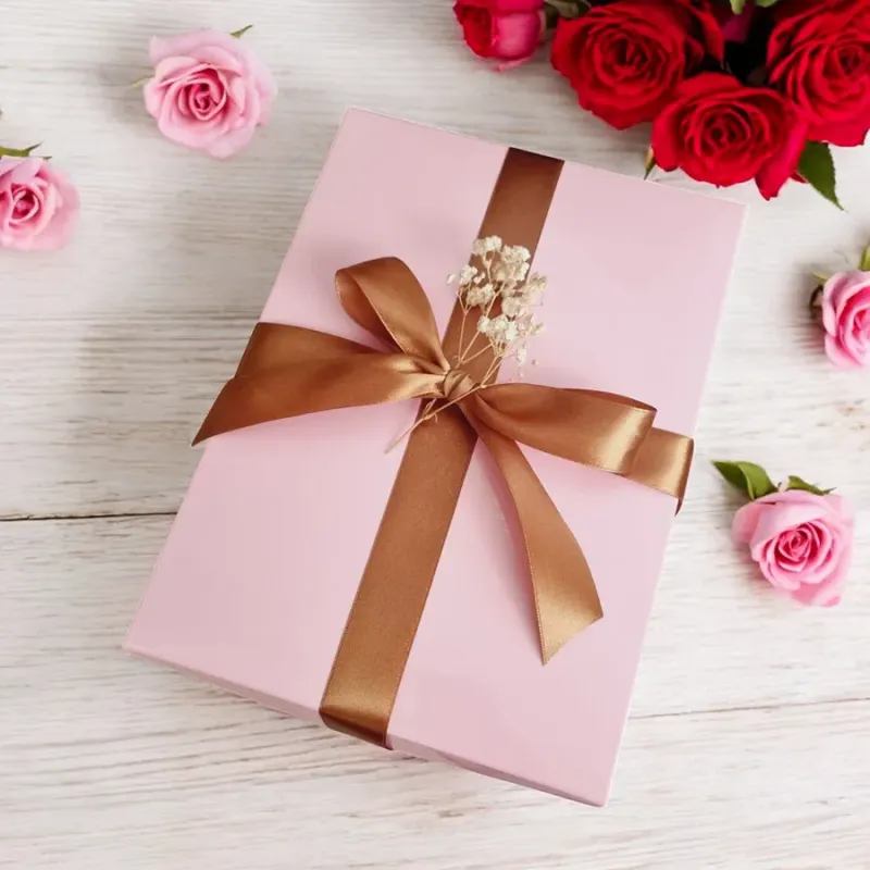 Zamknięte różowe pudełko przewiązane złotą wstążką