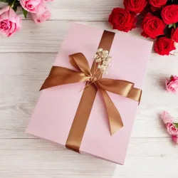 Zamknięte różowe pudełko przewiązane złotą wstążką