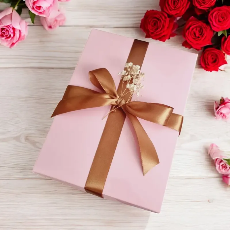 Zamknięte różowe pudełko przewiązane złotą wstążką