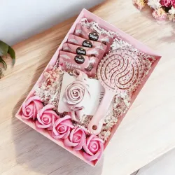 Wnętrze różowego pudełka z różową szczotką i gumką do włosów, różami mydlanymi oraz Ptasim Mleczkiem