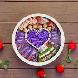 Zamknięte duże białe okrągłe pudełko z przezroczystą pokrywką i widoczną kompozycją czekoladową w środku