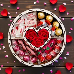 Wnętrze białego okrągłego pudełka z centralnym sercem, czerwonymi różami i słodyczami ułożonymi w przegródkach