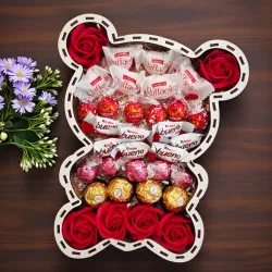 Wnętrze pudełka w kształcie misia z czerwonymi różami i słodyczami ułożonymi warstwami