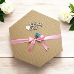 Zamknięte sześciokątne pudełko w naturalnym brązie przewiązane wstążką z napisem „kochanej babci”