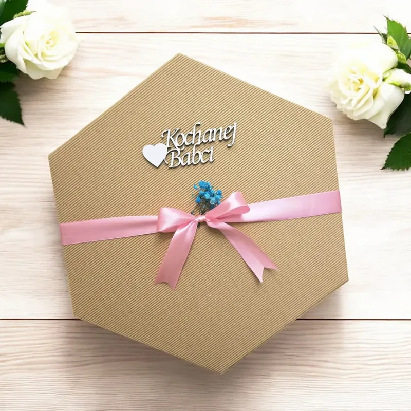 Zamknięte sześciokątne pudełko w naturalnym brązie przewiązane wstążką z napisem „kochanej babci”