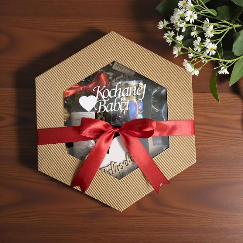 Zamknięte sześciokątne pudełko przewiązane czerwoną wstążką z drewnianym napisem „kochanej babci”
